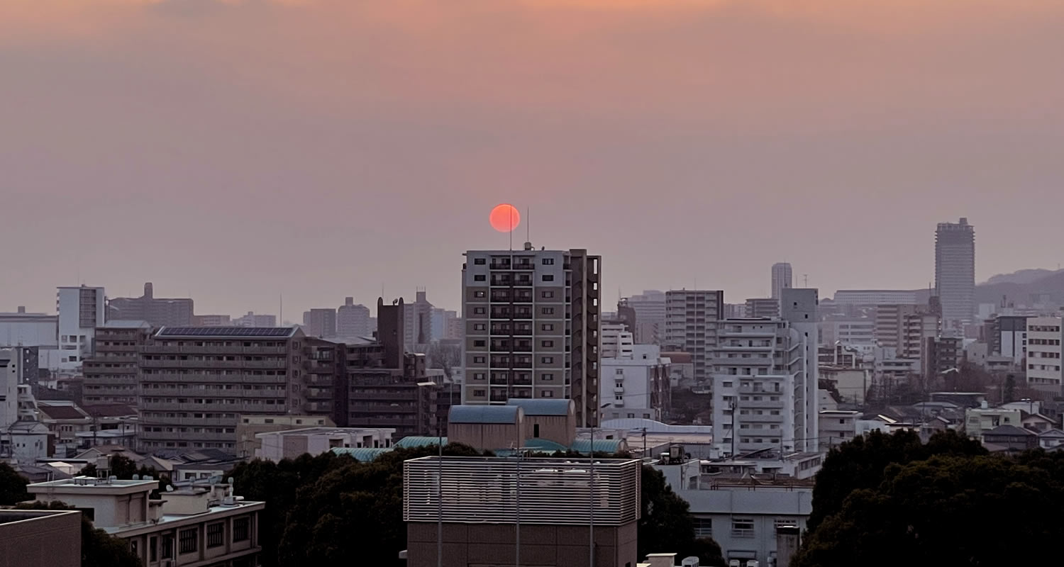 熊本市中央区プレミスト大江本町からみた夕陽と熊本駅近くにそびえる高層マンションのザ・熊本タワー